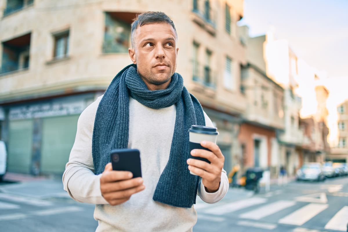 Ung mand står med en telefon i hånden klar til at finde et lokalt produkt eller ydelse. Billedet skal illustrere, hvor vigtigt det er at implementere lokal SEO (søgemaskineoptimering for lokale virksomheder)